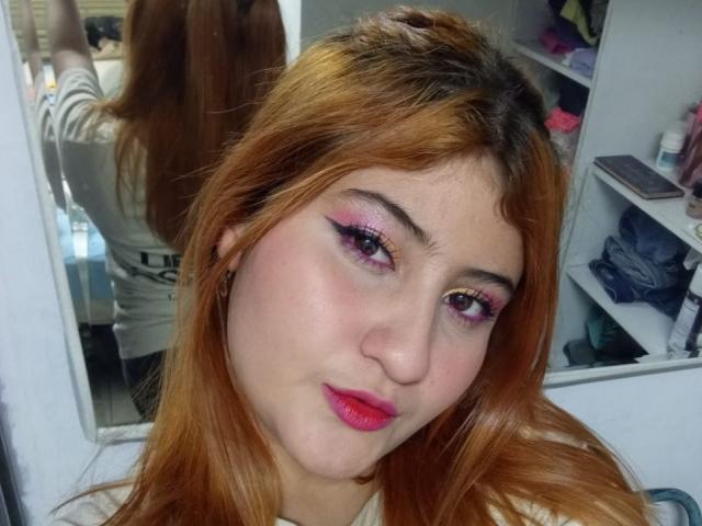Liebe Selene hat orangefarbenes Haar, pinke und violette Augen, pinken Lippenstift und ein süßes Gesicht mit einem leichten Lächeln. Ihr Spiegelbild zeigt ihren Rücken in einem Spiegel..