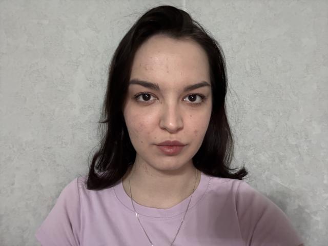 SandraRebar has a cute face with light skin, dark brown hair, small nose, and puffy lips. She's wearing a pink shirt and a thin necklace.