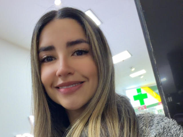 SofyaLane has long brown hair, a cute smile, and light brown eyes. She's wearing a fuzzy gray sweater and has a small nose piercing. Her skin is light brown.