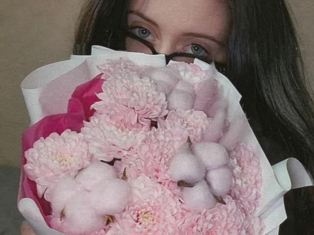 DanielleZiego's face is mostly hidden by a bouquet of pink chrysanthemums and fluffy white cotton balls, with only her eyes and black-rimmed glasses visible.