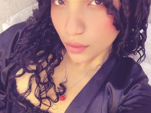 LightenStars has curly black hair, light brown skin, pink lips, and wears a black silk top with a red gem necklace, showing a subtle cleavage.