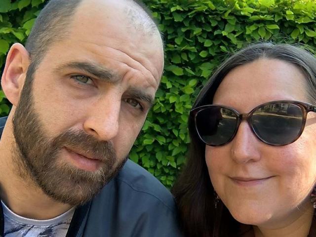CoupleLovve69 has a bald, bearded man with a slight smile and a woman with brown hair and black sunglasses, both looking at the camera. Her tits are small.