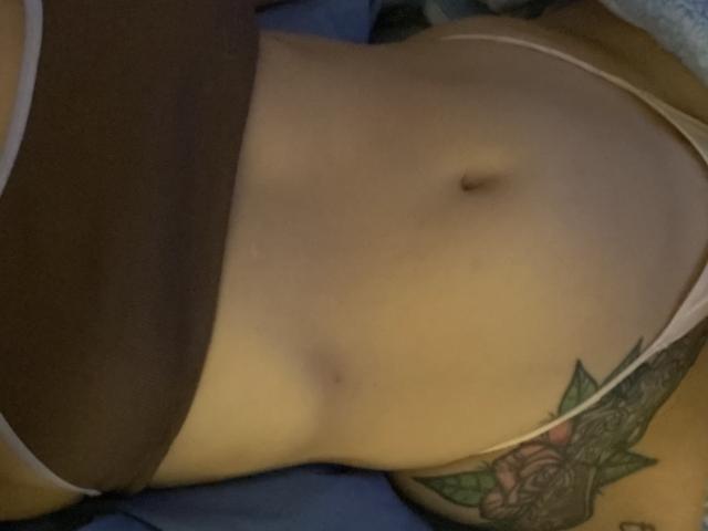 IsabellaPalacio's flat stomach, showing a small navel, brown underwear, and a colorful tattoo of a rose on her right side. Her light skin is visible.