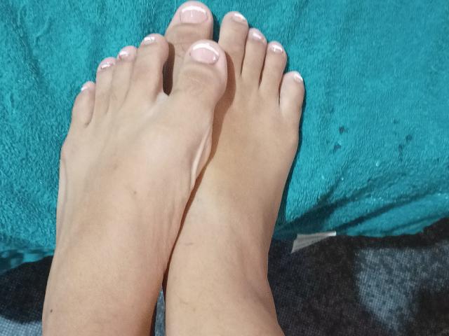 AngelRosa69's feet with pink-painted toenails, crossed at the ankles, resting on a turquoise towel. Her skin is light and smooth. She's barefoot, showing her toes clearly.