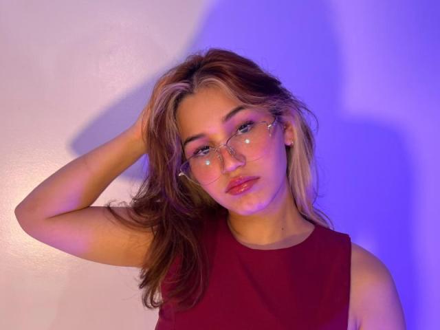 ElodieGardner with long brown hair, wearing clear glasses with star stickers, red sleeveless top, hand in hair, blue and purple light, serious expression, glossy pink lips.