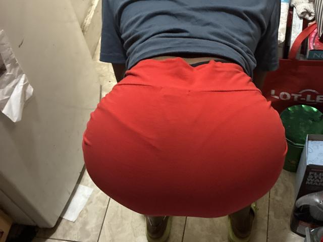 FantasyDreamz's large, red butt is in the foreground, wearing tight red shorts, with a blue shirt, standing with bent over posture, visible from the back.