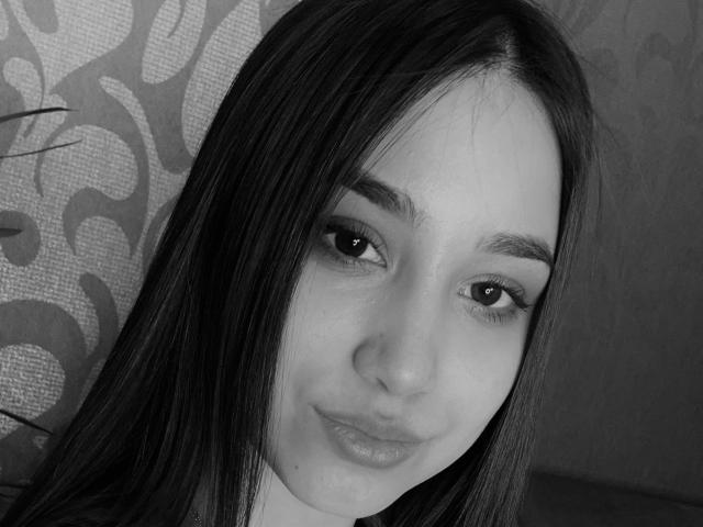 ShawneeLinderholm's face, black and white, with long dark hair, subtle makeup, and a slight smirk, showing her pouty lips and soft eyes. Her nose is centered.