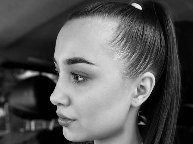 ShawneeLinderholm has a high ponytail with a visible hair clip, dark eyebrows, and a serious expression in a black-and-white photo. Her skin is smooth with subtle makeup.
