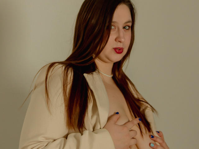 ViaLattea with long brown hair, red lipstick, blue nails, wearing an open beige shirt, covering her tits with hands, looking at camera, silver necklace, pale skin, slight smile.