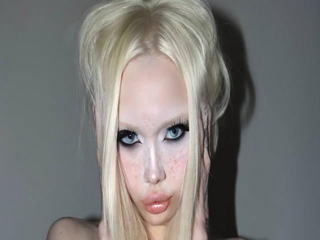 MargretMurak has pale skin, blue eyes, and long blonde hair in a messy updo. She's looking at the camera with heavy black eyeliner, pink lips, and freckles.