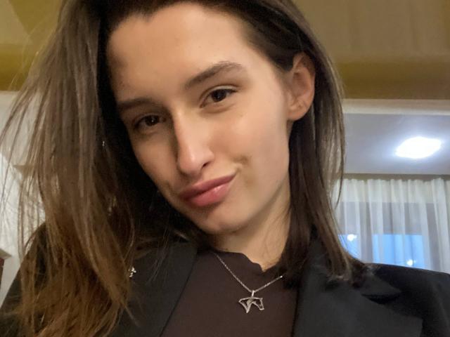 Charleen Tilton ha la pelle marrone chiaro, i capelli castani lisci e indossa una giacca nera con una collana d'argento. Ha un sorriso sulle labbra rosa..