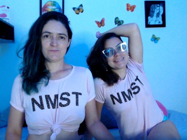 LunaVenus with medium tits in a pink tied-up shirt and pink shorts, smiling. LunaVenus with glasses, medium tits, pink shirt, and hand in hair, smiling. Blue-lit room.