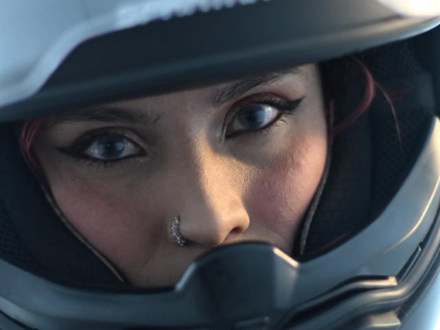 TifanySuarez's face in a helmet, blue eyes, black eyeliner, nose ring, slight blush, close-up, realistic digital art, focused expression, helmet visor partially covering her nose.