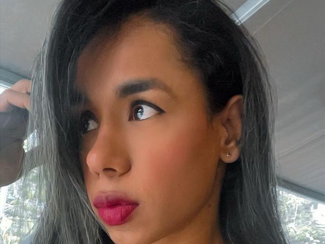 Iria's face, brown skin, gray hair, red lipstick, small earrings, hand in hair, looking to the side, subtle makeup, soft light, slight blush, gentle expression, sexy.
