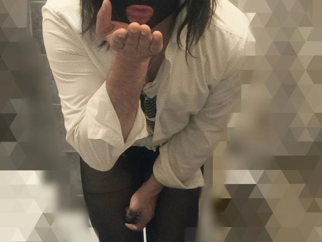 Alessia-hakken-sexy, draagt een witte blouse en een zwart masker, met haar hand in de buurt van haar mond, zwarte panty's en een zwart shirt, in een onscherpe, geometrische afbeelding..