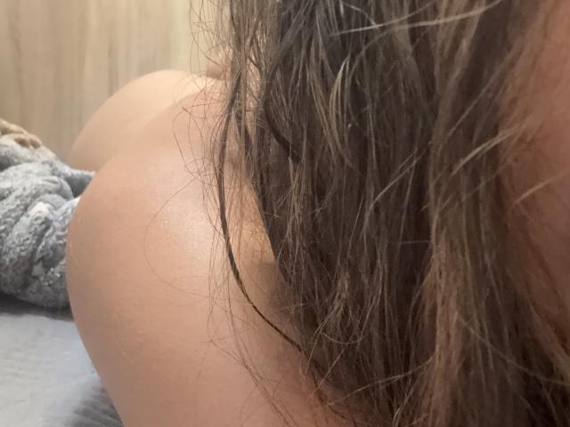 SofieWhite's ass is in the foreground, her wet brown hair partially covering it. Her tan skin is visible. A gray textured blanket is in the background.