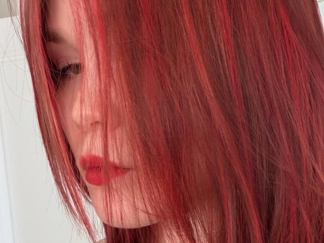 Donnetta Vannuland, con i capelli rossi e disordinati che le coprono il viso, le labbra rosse e la pelle pallida. I suoi occhi sono leggermente visibili, e guarda di lato. Il suo sedere non è presente nell'immagine..