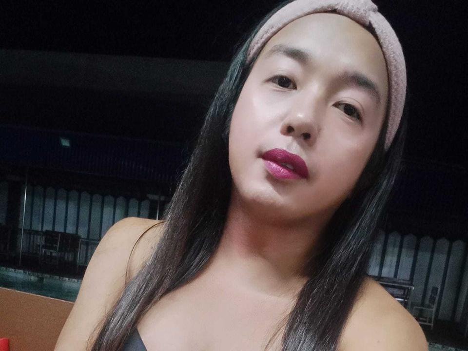 Criziah, con cabello negro largo, una diadema rosa y lápiz labial rosa, mostrando su linda cara y sus pequeños senos redondos en un selfie ligeramente inclinado..