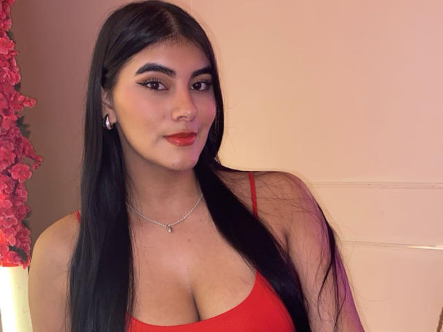 AlaraKey heeft lang zwart haar, rode lippenstift en een rood tanktopje dat haar grote borsten laat zien. Ze draagt een zilveren ketting en heeft een schattige, zelfverzekerde uitstraling..
