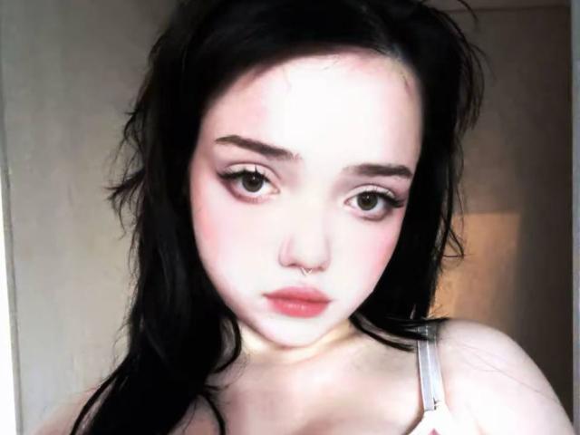 SuzieBrian ha la pelle chiara, i capelli neri, un piercing al naso e eyeliner rosa. Le sue labbra sono leggermente socchiuse. Indossa un reggiseno grigio. Il suo seno è piccolo..
