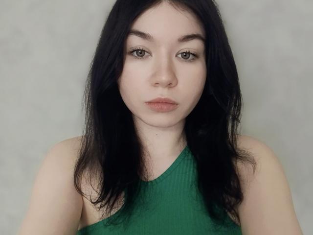 MaryaliceMally a la peau pâle, les cheveux noirs et lisses, les yeux verts, et elle porte un haut vert à bretelles et à côtes. Ses seins sont petits, et elle a une expression neutre..