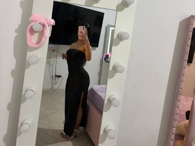 LaurentRay in a black strapless dress with a high slit, showing her ass, taking a mirror selfie, wearing pink heels, with a pink scrunchie on the mirror.