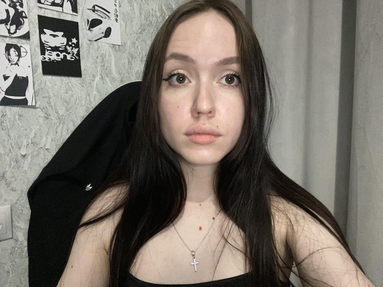 ZettaNetzley tem pele clara, cabelos longos e pretos e olhos castanhos. Ela está vestindo uma blusa preta, um colar com um crucifixo e tem um piercing no nariz. Seus seios são pequenos e sua vulva não está visível..