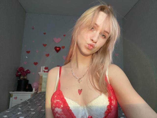 FlyFreedom, com cabelo rosa, lábios carnudos, vestindo lingerie de renda vermelha, colar com coração, pele clara, seios pequenos, mamilos rosa pálido, em pé em um quarto iluminado pelo sol, com mechas loiras..