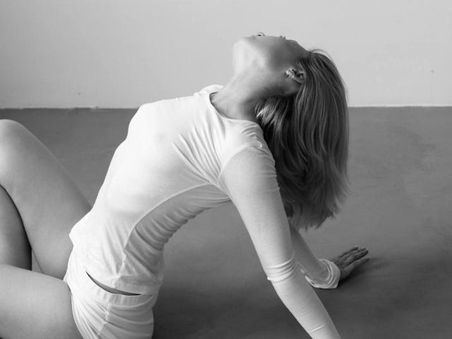 CrystalStoakley is on her knees, back arched, head tilted up, wearing a tight long-sleeve shirt and shorts, her blonde hair falling to the side, looking sexy.
