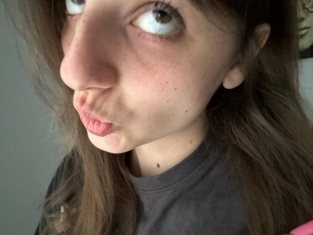 KarieMestler's puffy pink lips are puckered in a kissy face, with brown eyes looking to the side. She has freckles and a small mole on her chin.