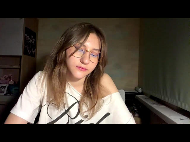LenoreSchontz with glasses, wavy brown hair, pink lips, white shirt, off-shoulder, sitting near piano, eyes closed, soft smile, relaxed, slight shadow on face.
