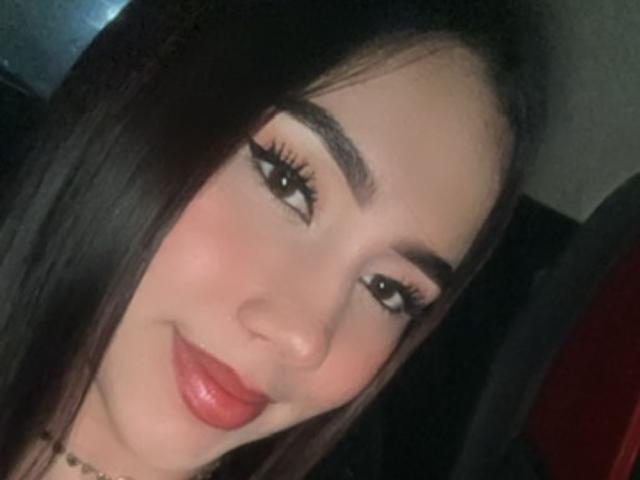 BibiSugarX has dark brown hair, thick eyebrows, long eyelashes, and red lipstick. Her cute, smiling face is slightly tilted with a soft, glowing complexion.