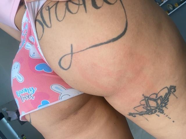 OnniOconor's butt in pink bunny-print underwear, showing a tattoo on the left cheek and another tattoo on the right thigh. Redness on the skin. Close-up.