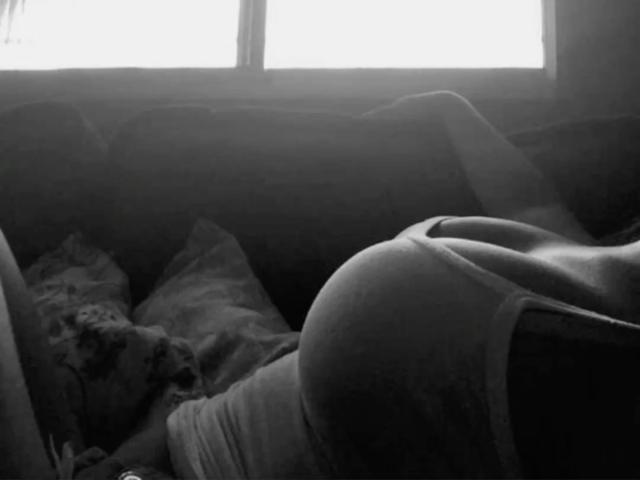 DianaFernandezz è sdraiata su un letto, indossa una canotta, e il suo grande sedere e i suoi piccoli seni rotondi sono ben visibili, con la testa leggermente fuori dall'inquadratura..