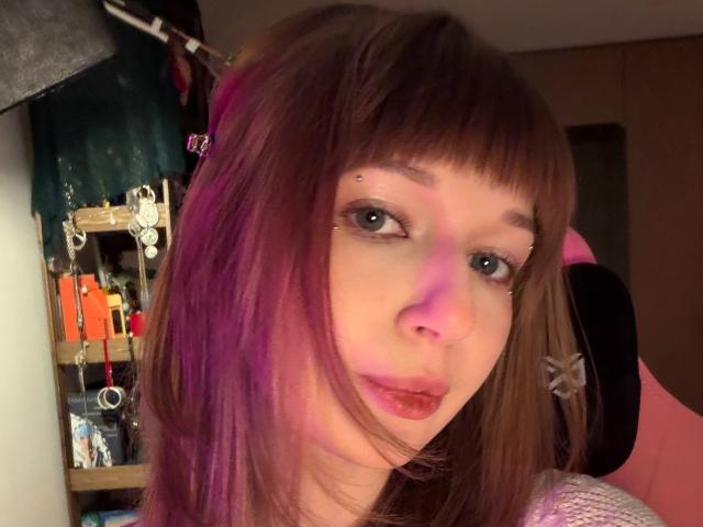 FerminaHilmer heeft roze-paars haar, een pony en een neusring, met paarse en roze lichtjes op haar gezicht, en lichtjes gespleten rode lippen. Haar borsten zijn niet zichtbaar..