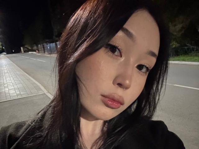 LorenzaMccaughan has shiny, glossy lips and dark, straight hair with a slight sheen, looking at the camera with a subtle, pouty expression in a night-time selfie.