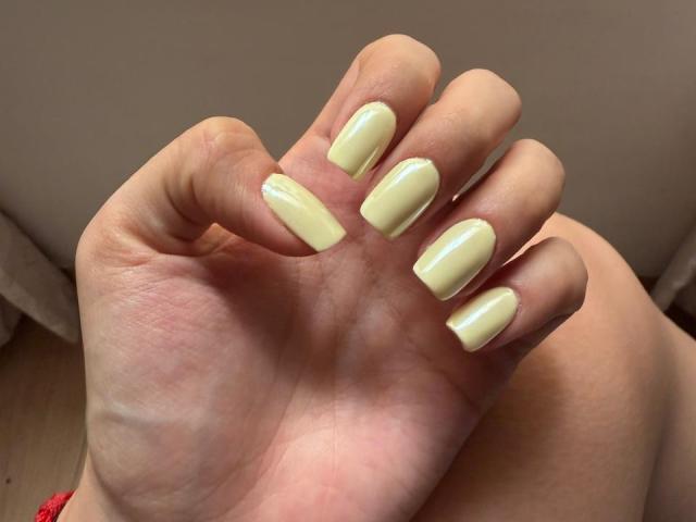 IsabellaJames's hand with pale yellow, glossy, square-shaped nails, fingers slightly curled, showing off her well-manicured, shiny, and polished fingernails.