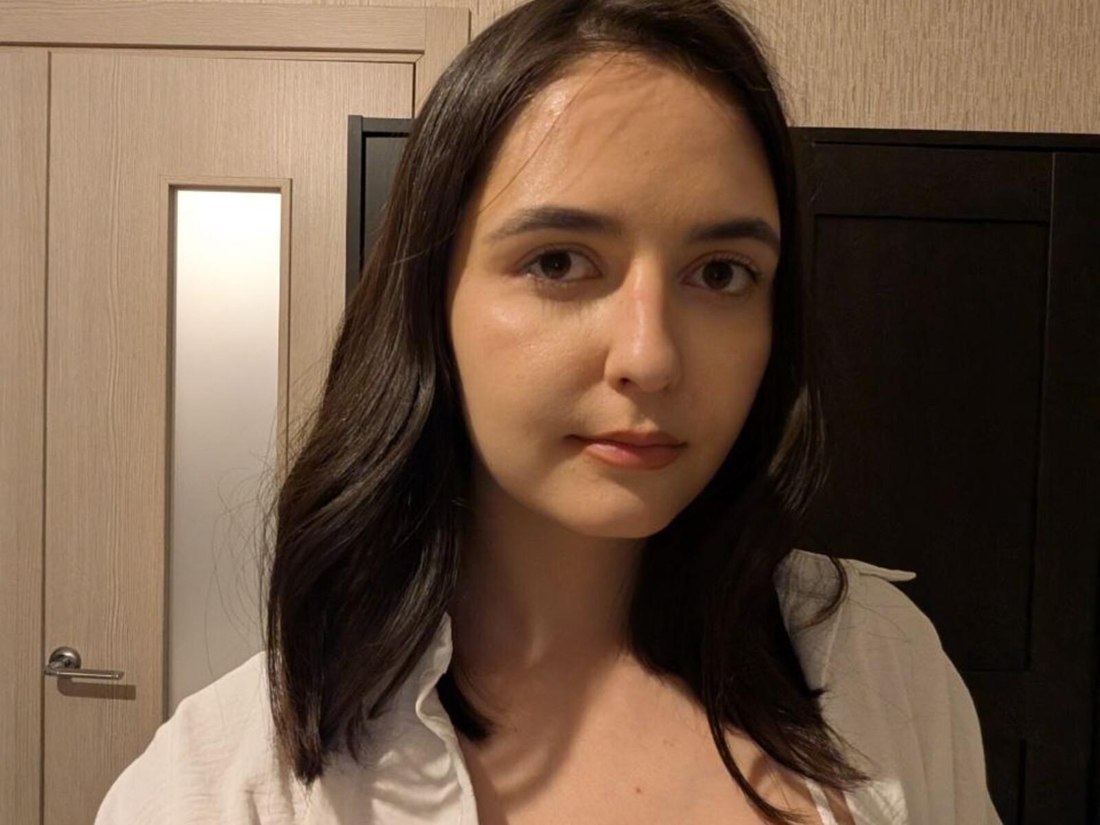 ChiDraft ha capelli castano scuro di lunghezza media, pelle chiara e occhi marroni. Indossa una camicia bianca, guarda leggermente di lato con un'espressione neutra. Il suo seno è piccolo..