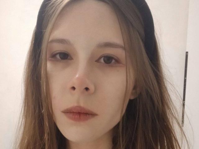 WendiWietzel's face, with light skin, brown eyes, and brown hair, wearing a black headband, has a neutral expression and slightly parted lips.