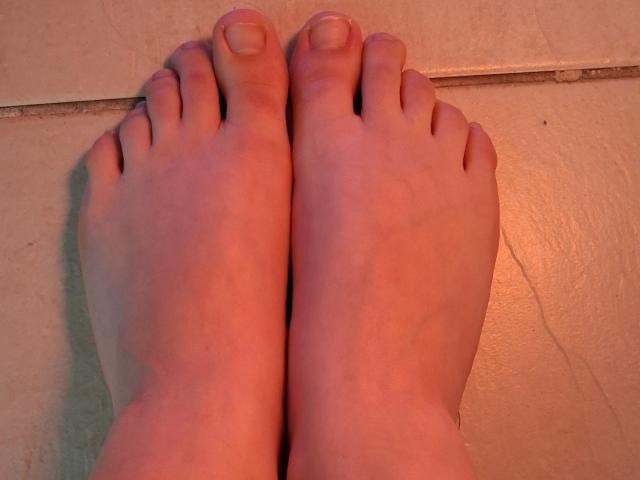 Les orteils de Marriam pointent vers le haut, avec une peau légèrement rosée et de petites ongles propres. Ses pieds sont positionnés proches l'un de l'autre sur une surface plane..
