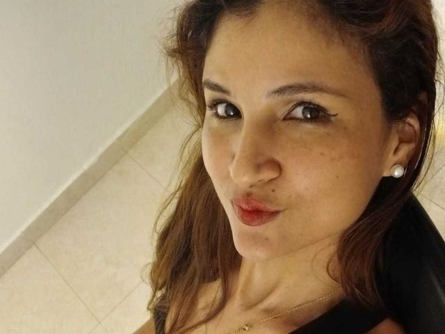 AmeliaBlond tiene ojos marrones, cabello oscuro y ondulado, y está haciendo pucheros con lápiz labial rojo. Lleva una blusa negra, aretes de perlas y un collar de oro. Sus pechos son pequeños..
