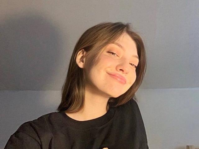 GigiWadkins has light skin, brown hair, and a small nose. She's wearing a black shirt, smiling slightly with a relaxed, closed-eye expression. Her tits are not visible.