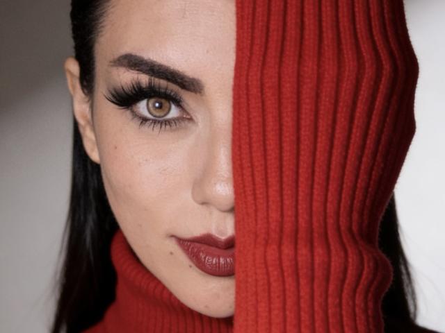 Le visage de ZoeeMar était à moitié dissimulé par une écharpe rouge côtelée, ne laissant apparaître que son œil marron avec de longs cils noirs, du rouge à lèvres rouge, et une peau claire, tandis que ses cheveux foncés étaient pour la plupart cachés..