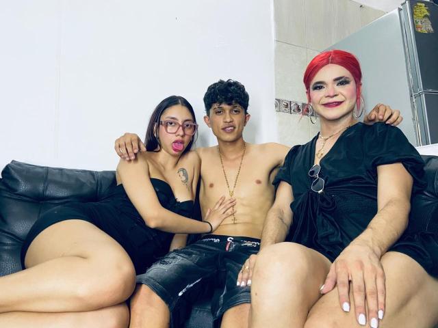 Tre persone, una con labbra rosse, vestito nero e occhiali a sinistra. Una persona, senza camicia, con capelli ricci al centro. Una persona, con capelli rossi, vestito nero e unghie bianche a destra..