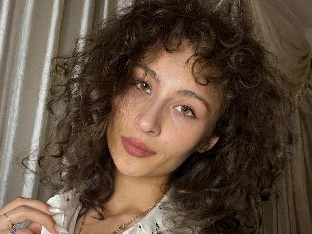 AlyceErway ha i capelli castano ricci, gli occhi castani e le labbra rosa con un sorriso appena accennato. Indossa una camicia bianca con pois neri, ed è molto carina e naturale..