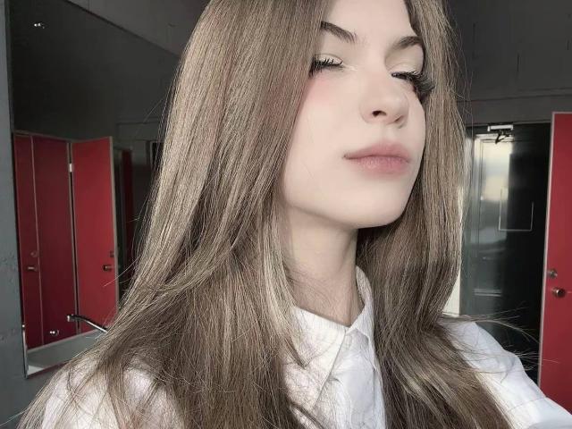 LauraleePenderel with long brown hair, closed eyes, and white shirt, looking slightly to the side with a subtle smile, showing her nose and lips. Boobs not visible.