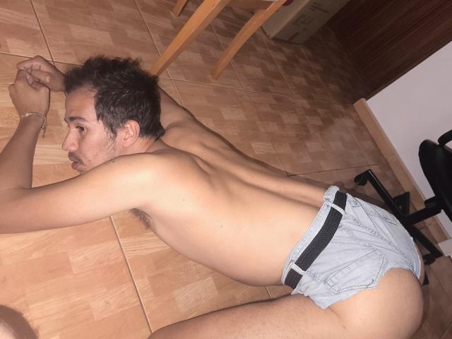 Teronn è inginocchiato, senza camicia, con la schiena rivolta verso la telecamera, indossando solo un paio di slip grigio chiaro che rivelano il suo sedere. Ha i capelli corti e scuri e un braccialetto..