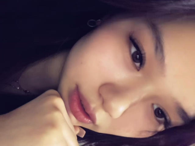 A selfie of LessieMelendy with her hand under her chin, showing her pouty lips and dark eyes, wearing subtle makeup and small hoop earrings. Her skin is smooth.