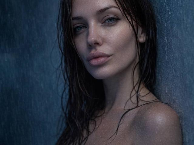 MissLover with wet brown hair, blue eyes, and slightly parted lips, looking directly at the camera. She's topless, showing her bare shoulders and upper chest. Moody, dark photograph.
