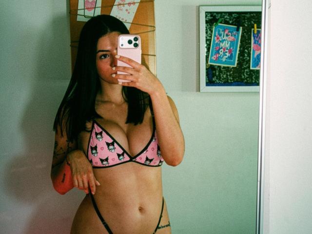 IsabellaJames in pink cat-face bikini, showing her big tits and slim waist, taking a mirror selfie with a pink iPhone, her black hair down, tattoo on right arm.
